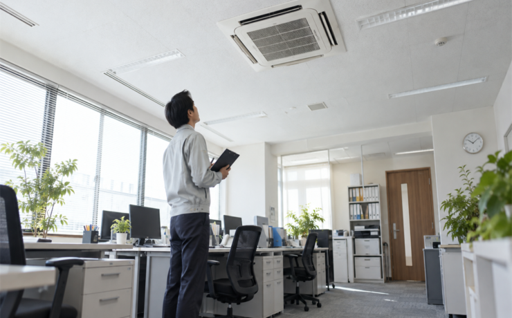 店舗の天井カセット形業務用エアコンと空調状態を見守る管理者