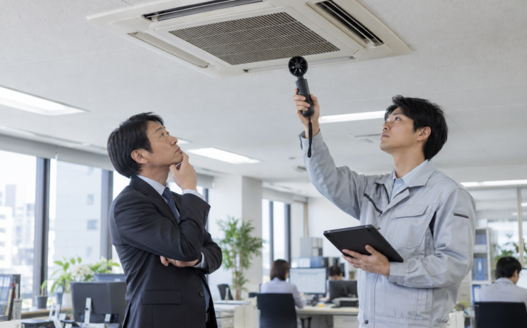 業務用エアコンの風量を測定する空調設備の点検担当者