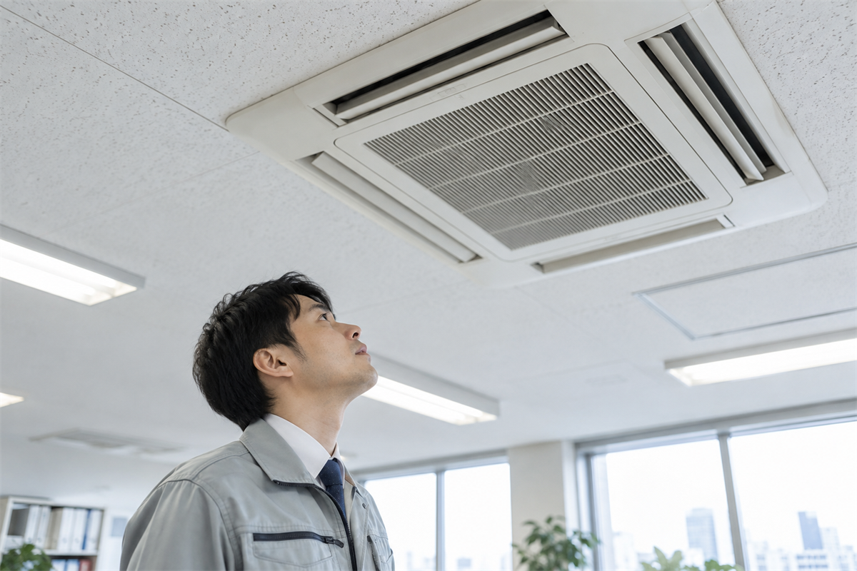床から業務用エアコンの吸込口を目視確認する担当者