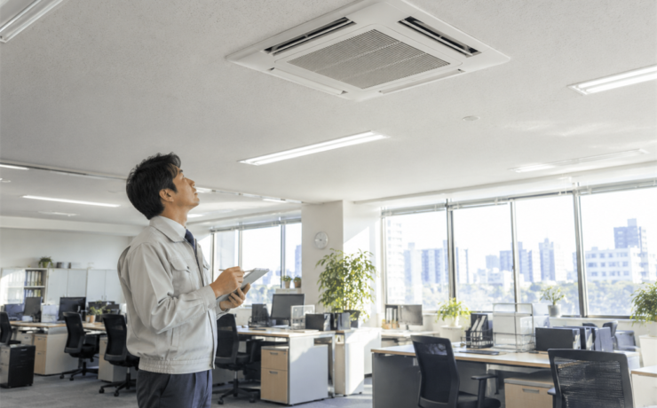 冬前にオフィスで業務用エアコンの暖房試運転を行う管理者
