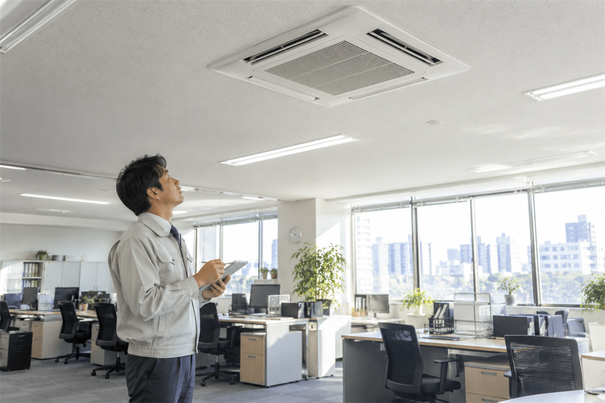 冬前にオフィスで業務用エアコンの暖房試運転を行う管理者