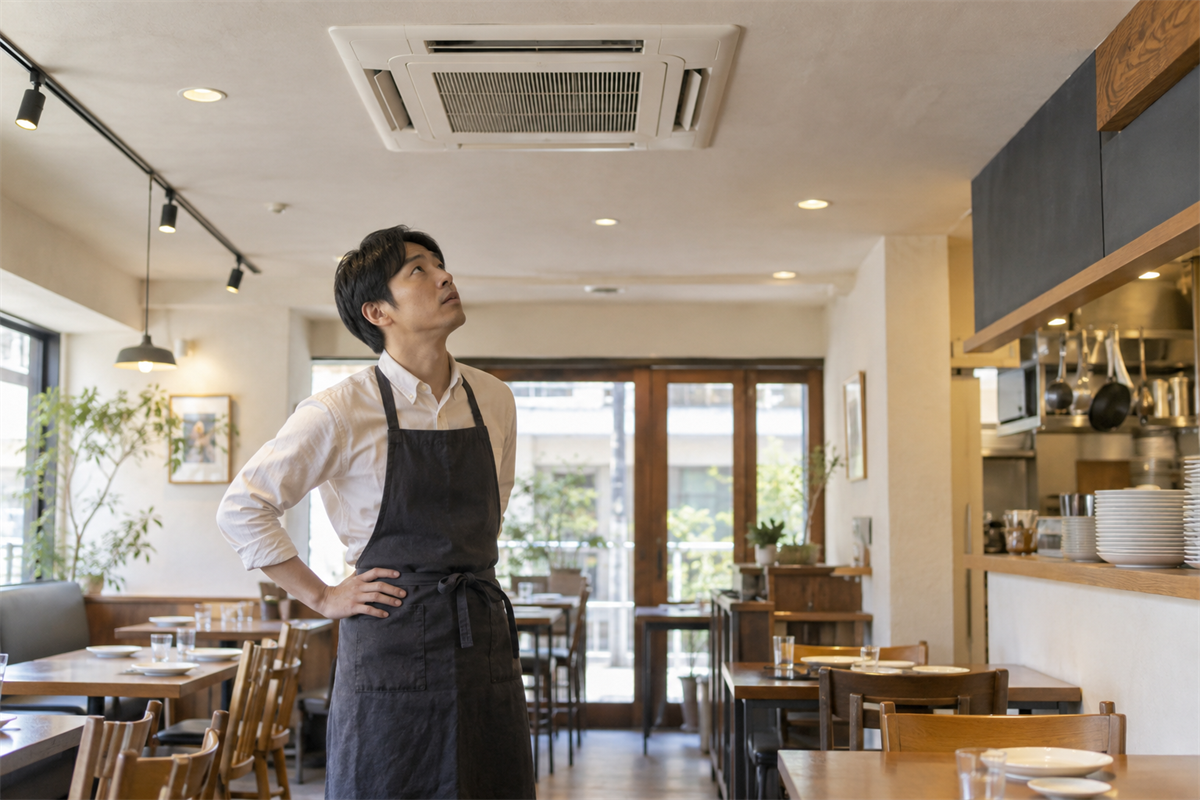 店舗で天井埋込形業務用エアコンの音を確認する担当者