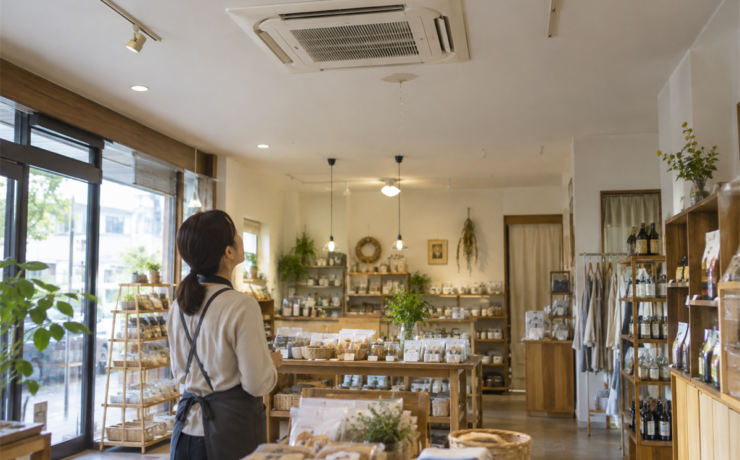 天井カセット形業務用エアコンからの水滴を離れて確認する店舗担当者