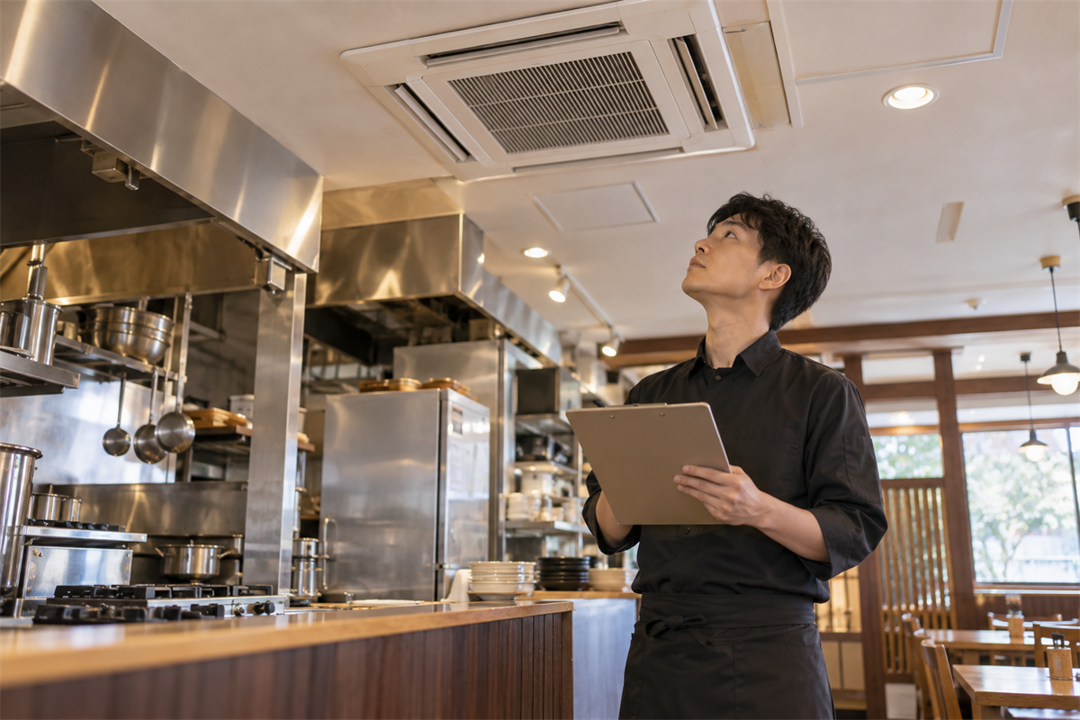 飲食店の調理場所と業務用エアコン吸込口の位置関係を確認するスタッフ